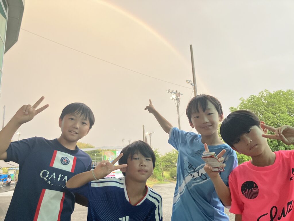 夏合宿で虹を背景に写真を撮る名古屋オーシャンズフットサルスクール桑名校の子どもたち