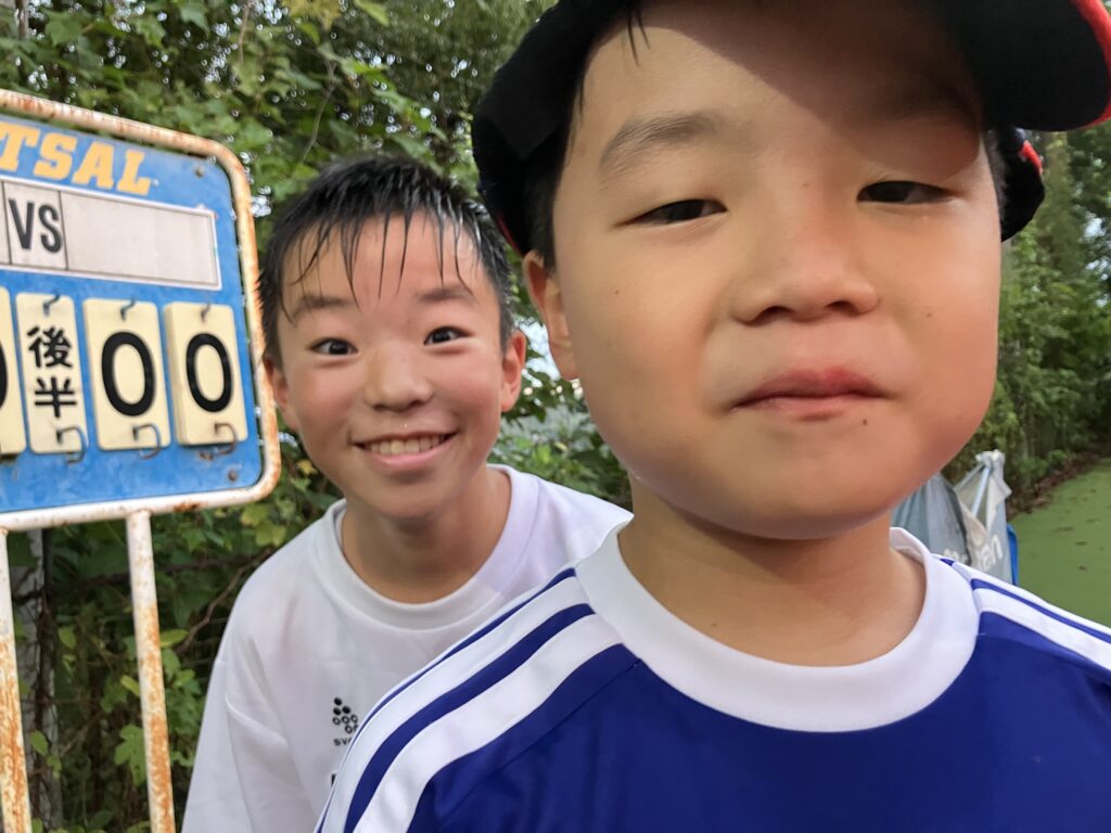 フットサルコートのそばで自然な表情を見せる2人の子どもたち